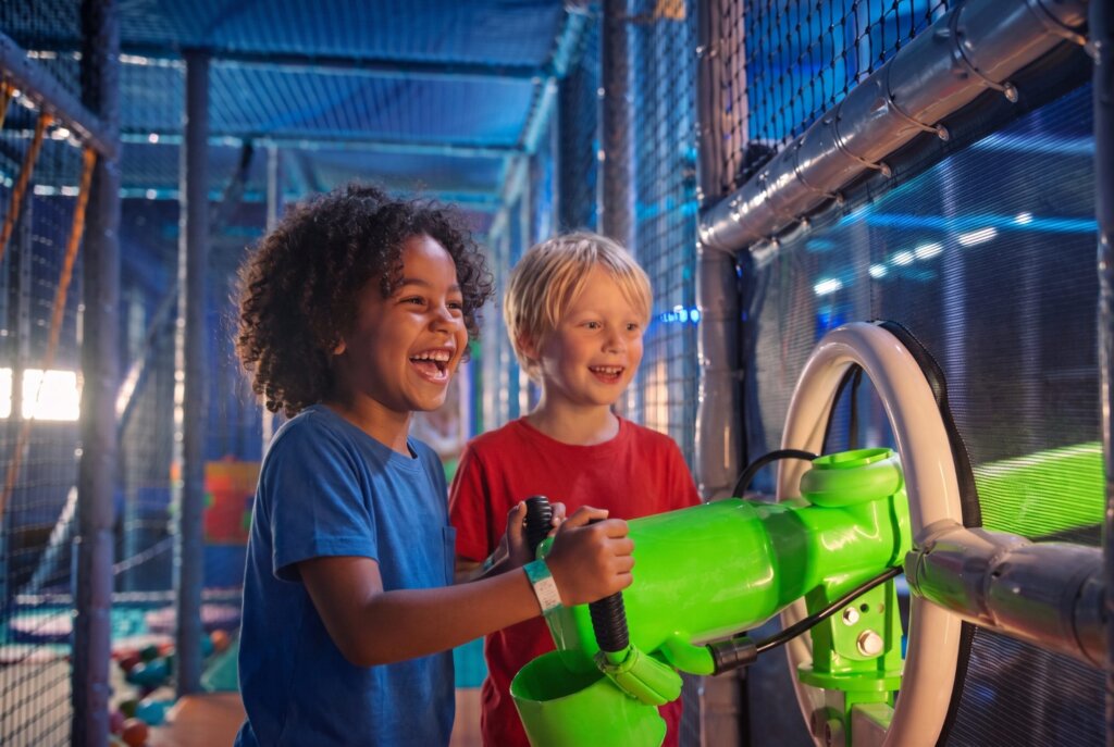 Twee lachende kinderen spelen in de indoor onderwaterspeelhal Atlantis van het Dolfinarium